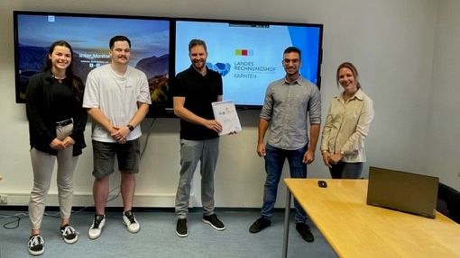 Gruppenfoto in einem Raum, zwei große Bildschirme im Hintergrund