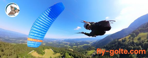 Foto von einem Paraglider, der der einen steilen Turn nach links macht. Rechts unten sieht man ein Logo und den Schriftzug: "Tandem Paragliding in Julian Alps. fly-golte.com"