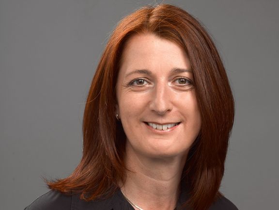 Foto von Magistra Doktorin Doris Brunner. Auf dem Foto hat sie kastanienbraune Haare, die über ihre Schultern fallen und braune Augen.