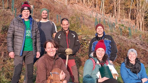 Studierende der FH Kärnten setzen Bäume für den guten Zweck – Gruppenfoto an einer lichten Stelle im Wald